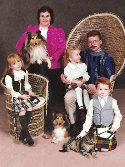 Vintage family portrait with two collies and a cat posed with the family in tartan